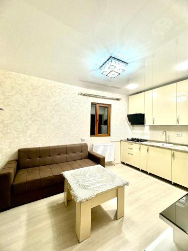 sala de estar con sofá marrón y cocina en gorgasali house, en Tiflis