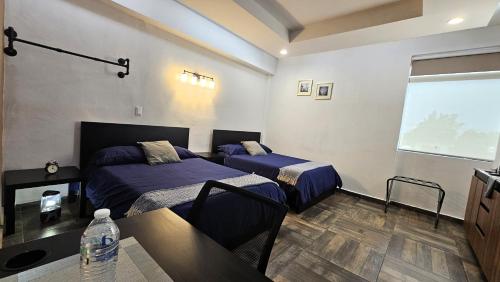 a bedroom with two beds and a table and a window at A21 SUITE BLACK MAX para 1 a 4 personas, Especialistas en CORTAS, MEDIANAS Y LARGAS ESTANCIAS en IZCALLI TEPOTZOTLAN perfecto para Familias, Turistas, Contratistas, Estudiantes, Empresas A sólo 5 min Izcalli 5 min Esmeralda 20 min Satélite 25 min AIFA in Cuautitlán Izcalli