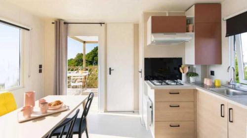 une cuisine avec une table et des chaises ainsi qu'une porte ouverte dans l'établissement Camping 3 étoiles - ccbaeih, à Moustiers-Sainte-Marie