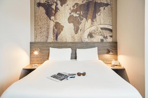 a bedroom with a white bed with a map of the world at Ibis Styles Hyères Rooftop & Spa in Hyères
