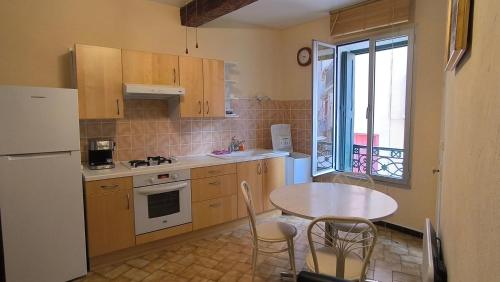 Il comprend une cuisine équipée d'une table, d'une table et d'un réfrigérateur. dans l'établissement Petit appartement au cœur du centre historique de Collioure, à Collioure