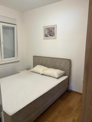 a bed in a white room with a bed frame at Prima in Bosanska Dubica