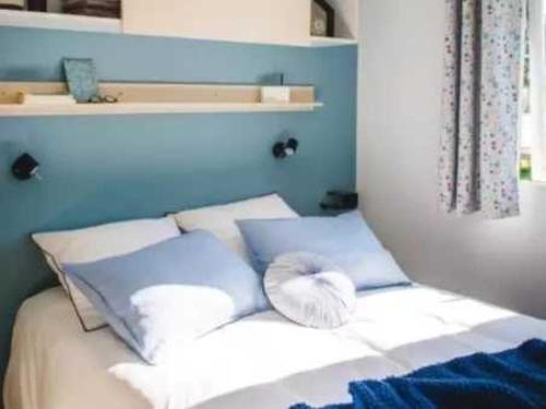 - un lit avec des oreillers blancs et un mur bleu dans l'établissement Camping 3 étoiles - Parc aquatique - eehagb, à Châtelaillon-Plage