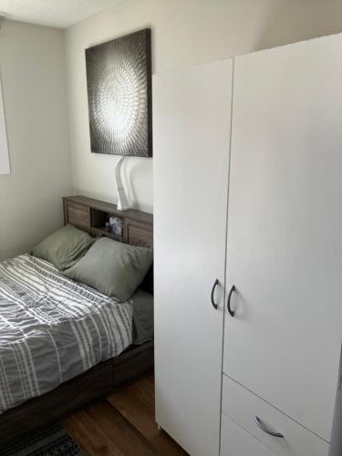 - une chambre avec un lit et une armoire blanche dans l'établissement Welcome to the Garden Room, à Kelowna