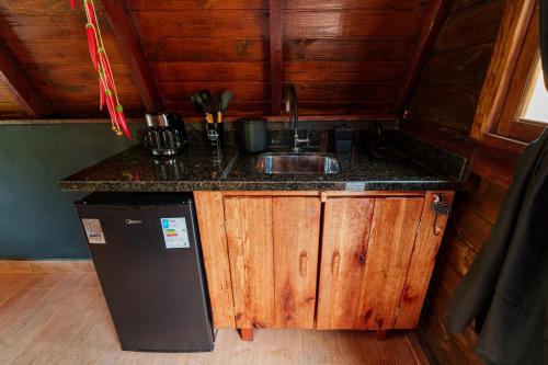 a kitchen with a sink and a refrigerator at Hotel Fazenda Gabro - A-frame in Apiaí