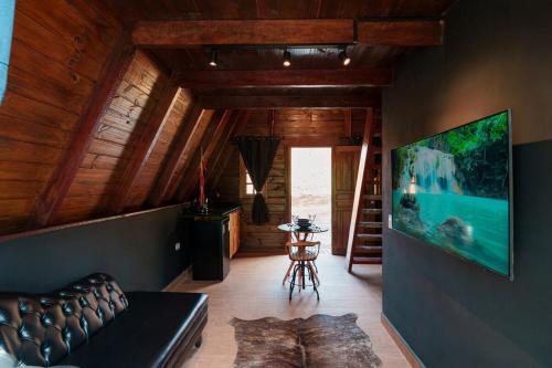 a living room with a couch and a tv on a wall at Hotel Fazenda Gabro - A-frame in Apiaí