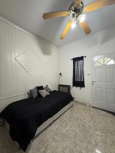 a bedroom with a black bed and a ceiling fan at Departamento in Mar del Plata