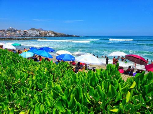 a group of people on a beach with umbrellas at Condominio Ocean reef in San Bartolo