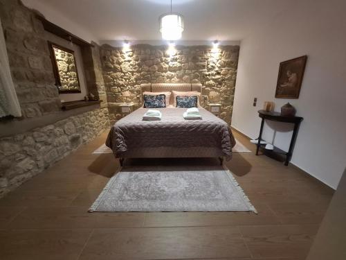 a bedroom with a bed and a stone wall at Elen's Suites Pramanta in Pramanta