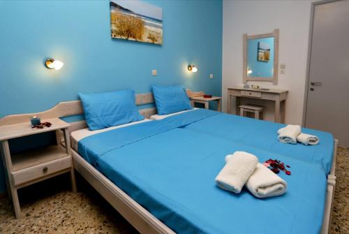 a blue bedroom with a large bed with towels on it at Villa Ermioni Studios in Limenas