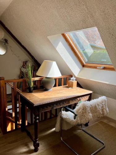 Cette chambre comprend une table avec une lampe et une fenêtre. dans l'établissement La petite maison, à Saint-Mars-dʼOutillé