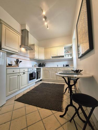 une cuisine avec des armoires blanches et une table et des chaises dans l'établissement Au plus près du Chateau !, à Chantilly