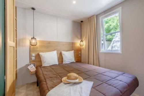 Un dormitorio con una cama con un sombrero encima. en Camping 3 étoiles - Piscine - ccafbhe, en Saint-Hilaire-de-Talmont