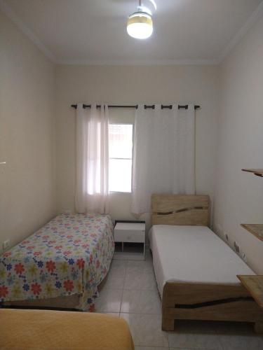 a bedroom with two beds and a window at LINDO SOBRADO PERTINHO DA PRAIA - WiFi 600 MEGAS in Bertioga