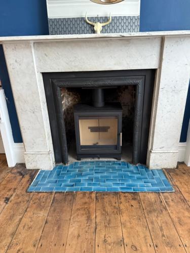 a fireplace with a blue tile floor in a room at Quirky spacious ground floor Victorian garden flat in Worthing