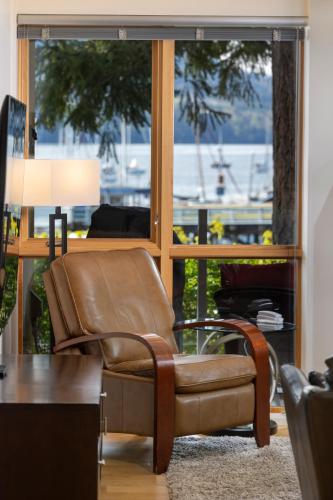 a brown leather chair in a living room with a window at Brentwood Bay Resort & Spa in Brentwood Bay