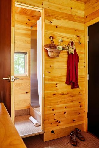 a bathroom with a wooden wall with a shower and a door at Postcard Cabins Chattahoochee in Suches