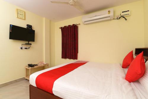 a bedroom with a bed with red pillows and a tv at Hotel O Andhra Pradesh Hotels Association in Vijayawada