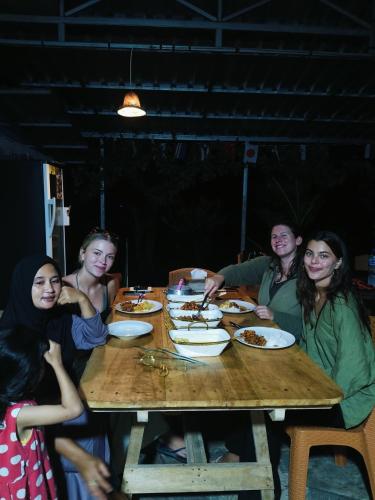 a group of people sitting around a table eating food at Raturinjani homestay in Selong
