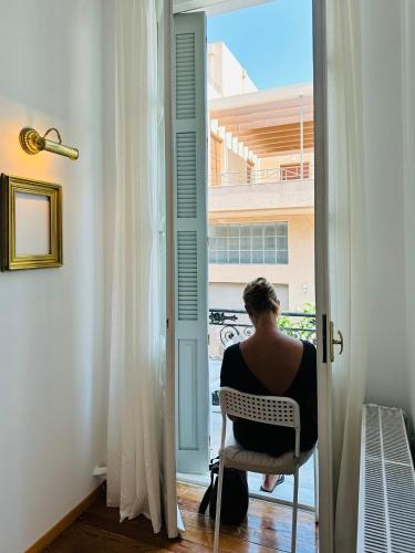 a woman sitting in a chair looking out a window at Pink Pineapple in Athens