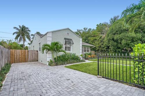 een huis met een hek en een stenen oprit bij Northwood Haven - Light-Filled Bungalow Close to Rybovich Marina in West Palm Beach