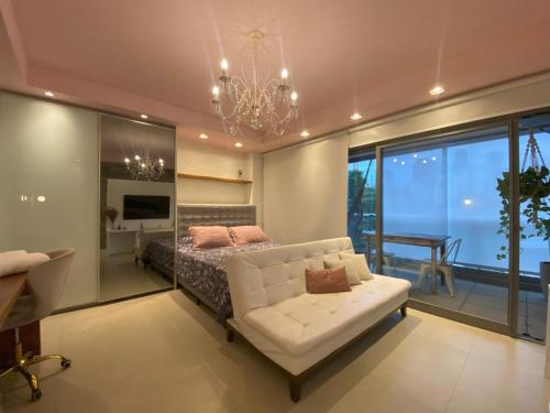 a bedroom with a bed and a couch and a chandelier at Cristal Studio Brooklin aero CGH Berrini in Sao Paulo