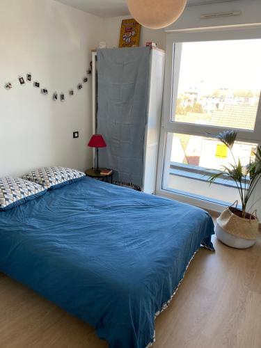 une chambre avec un lit bleu et une grande fenêtre dans l'établissement Magnifique duplex avec terrasse, à Romainville