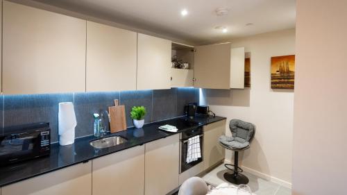 a kitchen with white cabinets and a black counter top at Mega5 Modern 2Bedroom Luxury Apartment Deansgate-2baths, 2toilets, free on site car park in Manchester
