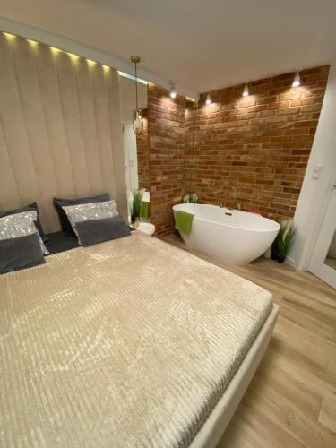a bathroom with a large bed and a bath tub at Apartament MoLoo I in Ostróda