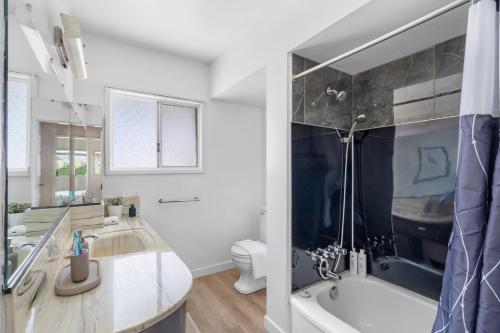 Un baño con bañera, lavabo e inodoro. en Spacious Home with Indoor Pool, en Vancouver