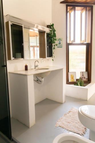a bathroom with a sink and a mirror and a toilet at Marola Hostel in Ubatuba