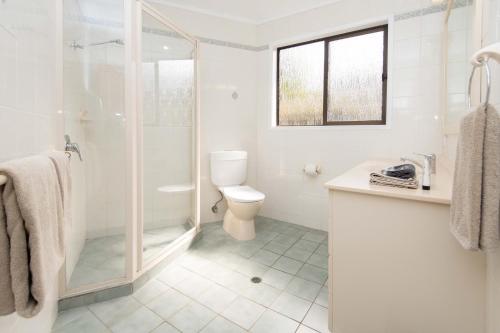 a white bathroom with a shower and a toilet at Whispering Pines Cottages in Burnt Pine