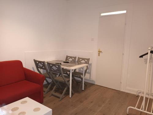 a room with a table and chairs and a red couch at Appartement entier au RDC - Ideal pour travailleurs ou voyageurs en famille jusqu à 6p in Mulhouse
