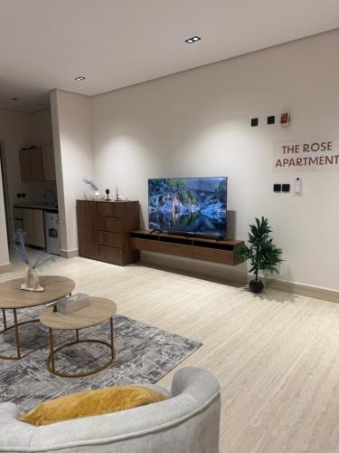 a living room with a couch and a tv on a wall at The Rose Apartment الدمام in Al Fayşalīyah