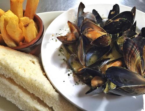 a plate of food with mussels and a sandwich and french fries at The Bugle Inn in St Austell