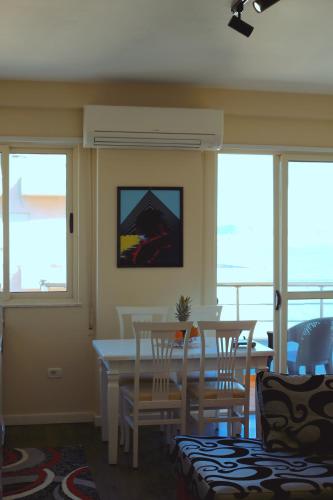 a dining room with a table and chairs and windows at Beachfront Bliss Central 2BR Apartment in Durrës