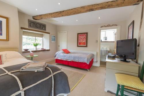 a bedroom with a bed and a flat screen tv at Church End Cottage in Milton Keynes