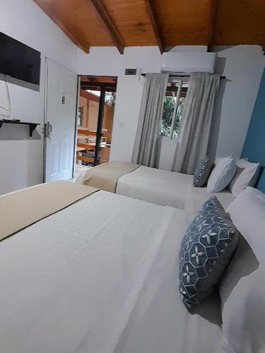 a bedroom with two white beds and a window at Alojamiento mei-mei in Puerto Iguazú