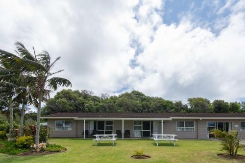 a house with two picnic tables in the yard at Daydreamer Apartments in Burnt Pine