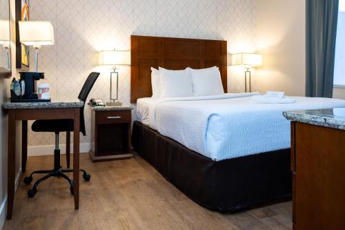 a bed in a hotel room with a desk and a bed at Quality Inn & Suites in Vancouver