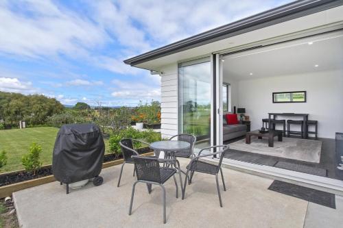 a patio with a table and chairs and a couch at Luxury B&B Steps Away From Most Wedding Venues of Kumeu! in Kumeu