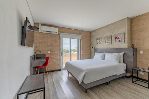 a bedroom with a large bed and a red chair at Hotel Quinta Norte Chipichape in Cali