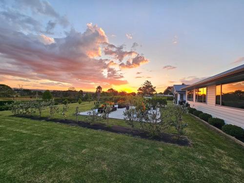 a backyard with a row of trees and a house at Luxury B&B Steps Away From Most Wedding Venues of Kumeu! in Kumeu