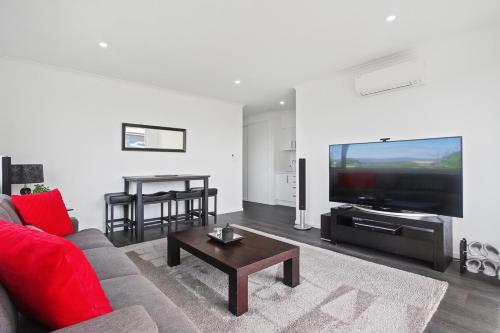 a living room with a red couch and a flat screen tv at Luxury B&B Steps Away From Most Wedding Venues of Kumeu! in Kumeu