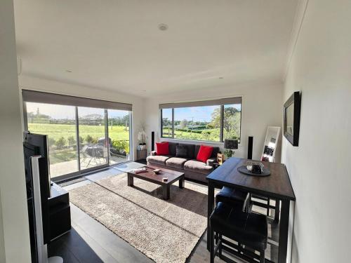 a living room with a couch and a table at Luxury B&B Steps Away From Most Wedding Venues of Kumeu! in Kumeu
