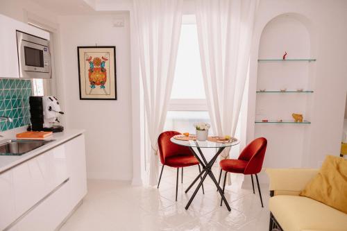 Casa BoMa في مينوري: مطبخ مع طاولة وكراسي حمراء في الغرفة