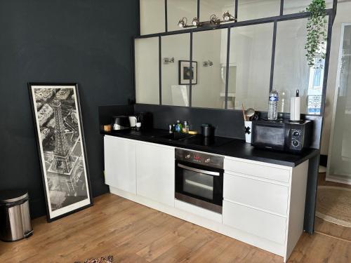 une cuisine avec des armoires blanches et un micro-ondes dans l'établissement Magnifique F2 Centre Historique Montpellier, à Montpellier