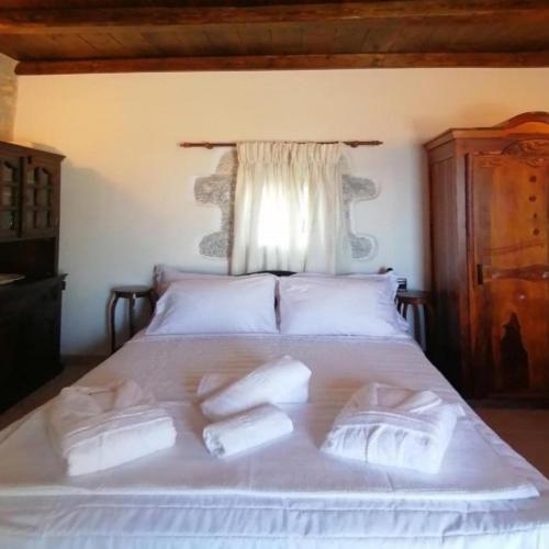 a bed with four pillows on it with a window at Mani Fort Charabos in Ayía Kiriakí