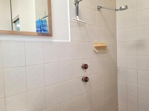a white bathroom with a shower with a mirror at Catalina Cottage in Port Moonta