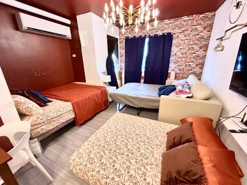 a room with two beds and a couch in it at Near Airport Beach SwimmingPool HotShower NoElevator Plumera Mactan Condo in Lapu Lapu City